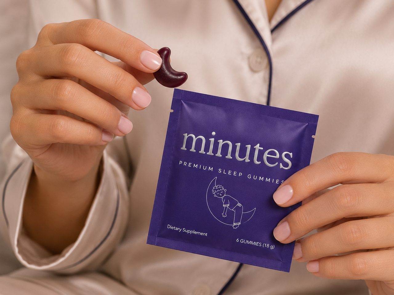 A Minutes sachet and one blackberry gummy held in hand, satin pyjamas